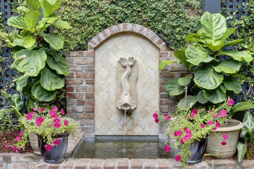 a statue in a brick wall with flowers and plants at Under The Red Door On Monterey in Savannah