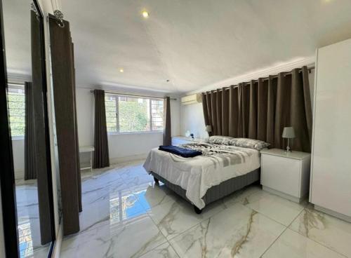 Chamane Place في ديربان: غرفة نوم بسرير وأرضية رخام كبيرة