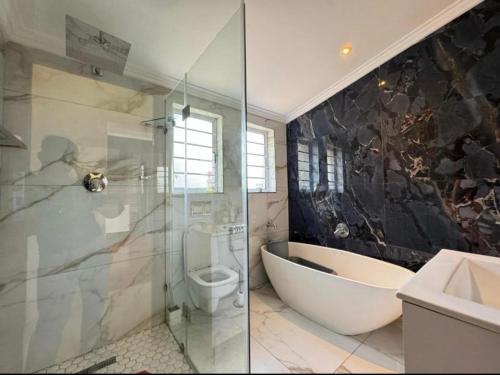 Chamane Place في ديربان: حمام مع حوض استحمام ومرحاض ومغسلة