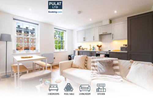 a living room with a white couch and a kitchen at 3BR Flat By Pulat Short Lets & Serviced Accommodation London With Pool Table, SmartTV & AC in London