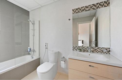 a bathroom with a toilet and a sink and a mirror at 3BR Luxurious Villa pool view DAMAC Hills 2 in Dubai