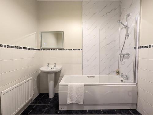 een badkamer met een ligbad en een wastafel bij Waterfoot Penthouse Apartment in Newcastle