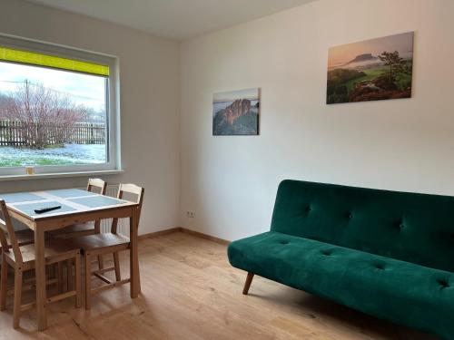 a living room with a green couch and a table at 4-Steine-Blick, Wohnung "Zum Winterberg" in Schöna