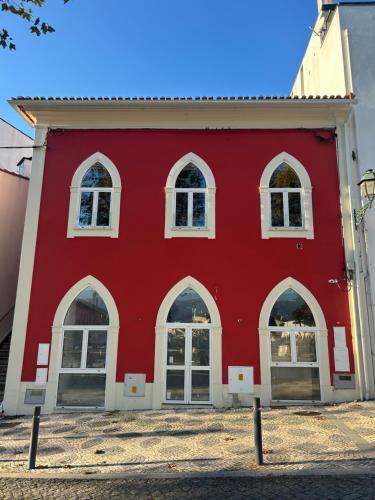 a red building with arched windows at A Casa da Praça - The Square House in Miranda do Corvo