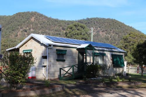 una casa con paneles solares en ella con una montaña en Starline Alpacas Farmstay Resort, en Broke