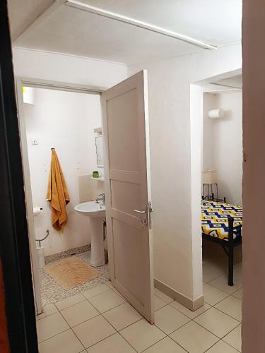 a room with a bathroom with a sink and a bed at Hôtel Les Palmiers in Ouagadougou