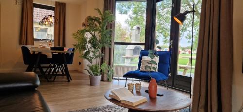 a living room with a blue chair and a table at Lakefront Cottage Gelderland BBQ & tuin 6pers in Ewijk