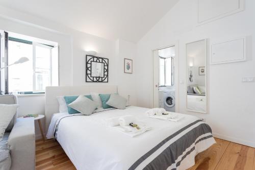 a white bedroom with a large white bed with towels on it at Apartments Center Alfama in Lisbon
