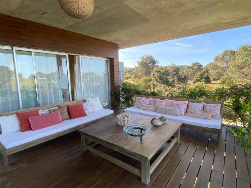 un soggiorno con divani e un tavolo su una terrazza di Casa de Piedra Village del Faro a José Ignacio