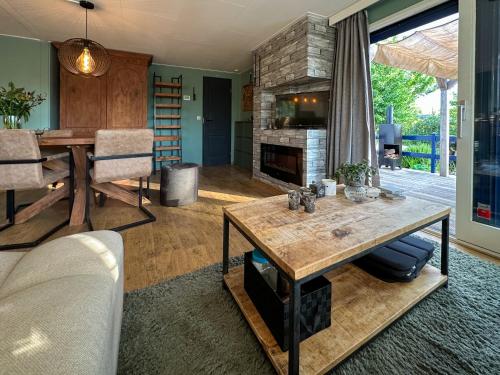 a living room with a table and a fireplace at Cozy escape Beach&Nature near Den Bosch - 4 PS chalet met veel privacy en rust! in Lith