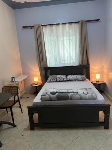 a bedroom with a bed with a window and two tables at Aurora two in Kampala