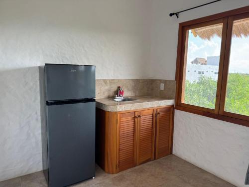 a kitchen with a refrigerator and a sink and a window at Casa del Sol Holbox - Self Check In in Holbox Island