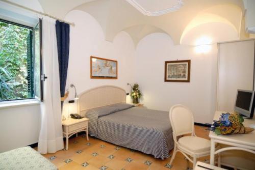 a bedroom with a bed and a table and a window at Hotel Bellevue Suite in Amalfi