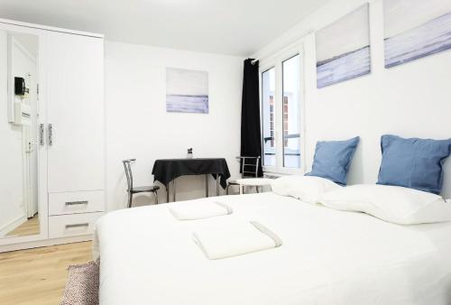 a white bedroom with a large bed with blue pillows at Studio Near Metro & Marais & Hotel de Ville & Seine in Paris