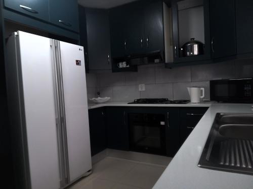 a kitchen with black cabinets and a white refrigerator at 83 Ocean View in Port Shepstone