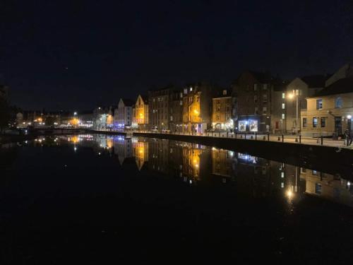 a city at night with lights reflecting in the water at Modern loft style apartment in converted church in Edinburgh