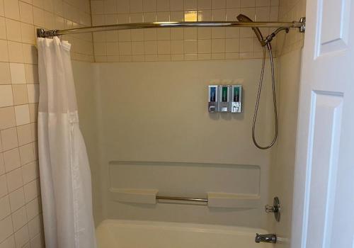 ein Bad mit einer Dusche mit einem weißen Duschvorhang in der Unterkunft Porky's Lodge, Bar & Grill in Georgetown