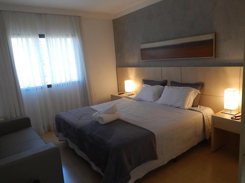 a bedroom with a bed with two lamps and a window at Flat Hotel Mont Blanc Premium in Ribeirão Preto