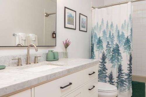 a bathroom with a sink and a shower curtain with trees at Group Escape: 6BR Hot Tub, Sauna, Game Rm & Garage in Lemeta