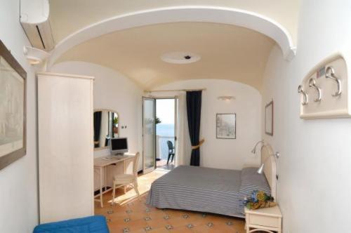 a bedroom with a bed and a desk with a computer at Hotel Bellevue Suite in Amalfi