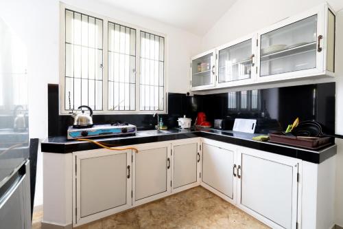 a kitchen with white cabinets and black counter tops at Lira Unawatuna in Unawatuna