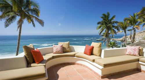 a patio with a couch and palm trees and the ocean at Casa Edwards II in San José del Cabo