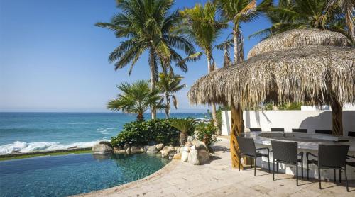 a swimming pool with a table and chairs and the ocean at Casa Edwards II in San José del Cabo