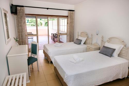a hotel room with two beds and a balcony at Residencial San Fernando in Ponte da Barca