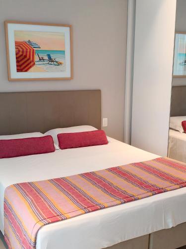 a bedroom with a bed with two red pillows at Unique Residence Lindo Apartamento Vista Mar e garagem in Santos