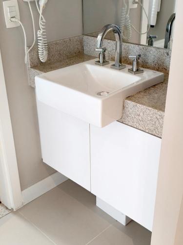a bathroom with a white sink and a mirror at Unique Residence Lindo Apartamento Vista Mar e garagem in Santos