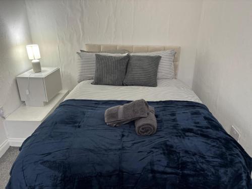 een bed met een blauwe deken en twee handdoeken erop bij Zinoc Seaside Apartment in Murton