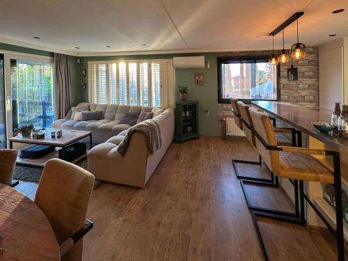 una sala de estar con un sofá y una mesa en Cozy escape near Den Bosch - 4 PS chalet met veel privacy en rust!, en Lith