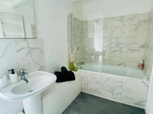 a white bathroom with a sink and a shower at L'Escapade Charentaise Central et calme in La Rochefoucauld