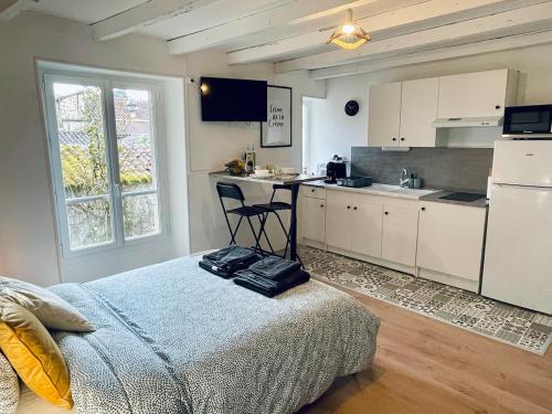a bedroom with a bed and a kitchen with a table at L'Escapade Charentaise Central et calme in La Rochefoucauld