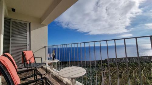 a balcony with chairs and a table and a view of the ocean at Pearl Retreat by Holiday Rental Madeira in Câmara de Lobos