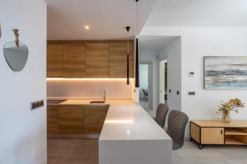 a kitchen and dining room with white walls and wood cabinets at Sanset Waves with a sea view! in Benidorm
