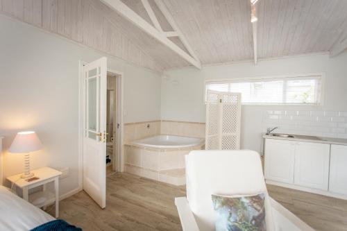 Una habitación blanca con una bañera, una cama y una mesa. en Slanting Acers - Unit B, en Wilderness