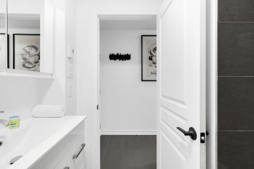 un bagno bianco con lavandino e specchio di Pristine Parc Avenue Pad With Parking a Montréal