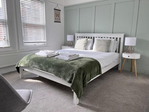 a bedroom with a white bed with a green blanket at Stylish Caversham Town-House Free Parking & Garden in Caversham