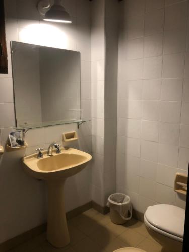 een badkamer met een wastafel en een spiegel en een toilet bij La Dorada Inn in Luján