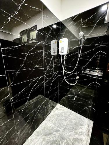 a bathroom with a black tiled wall with a shower at Dee Dee Apartments ChumPhae in Chum Phae