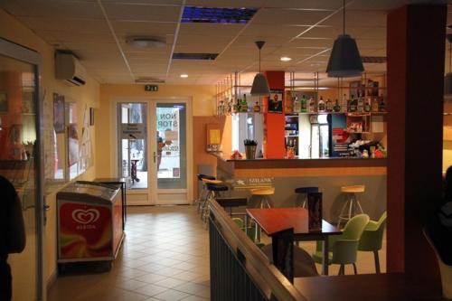 a restaurant with a counter and a bar with chairs at Teke Bowling Centrum és Sport Panzió in Szeged