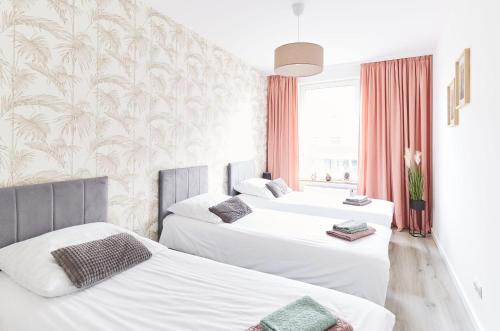 Dos camas en una habitación de hotel con blanco. en SkyTravel 26 Apartament Pileckiego Nowy Dwór Mazowiecki Airport Modlin 24H, en Nowy Dwór Mazowiecki