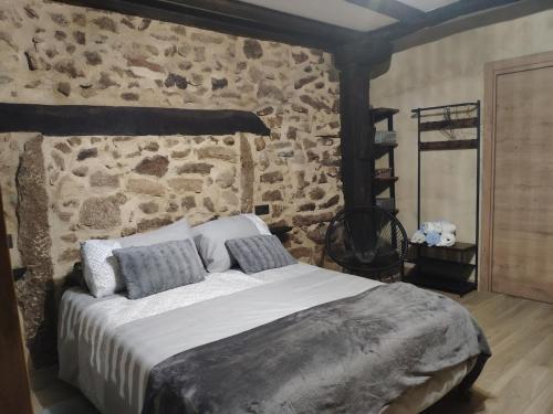a bedroom with a large bed with a stone wall at Bosque animado in La Alberca