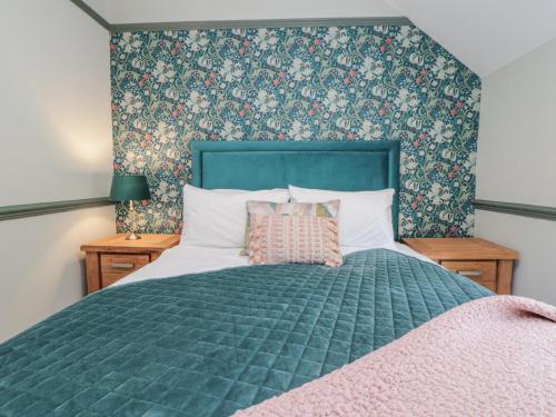 a bedroom with a green bed with a pink blanket at Inglenook Cottage in Guisborough