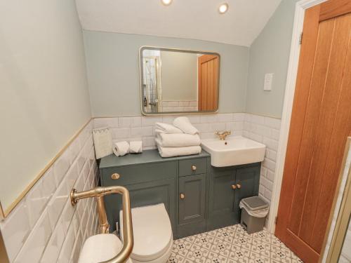 a bathroom with a sink and a toilet and a mirror at Inglenook Cottage in Guisborough
