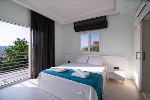 een witte slaapkamer met een bed en een groot raam bij Villa Mira in Ovacik
