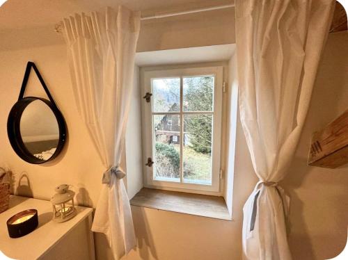 a bathroom with a window with white curtains at Kouzelná chalupa u lesa in Česká Lípa