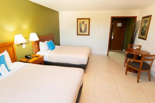 a hotel room with two beds and a chair at Baja Inn Hoteles La Mesa in Tijuana