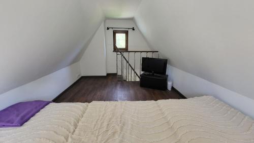Un dormitorio con una cama y un televisor en un ático. en Chata so záhradou, en Lutila